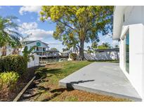 Inviting backyard space with a concrete patio, lush greenery, and waterfront access via a private dock at 8704 Thornwood Ln, Tampa, FL 33615