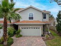 Charming two-story home with a terracotta roof, brick driveway, and lush tropical landscaping at 1259 Ribolla Dr, Palm Harbor, FL 34683