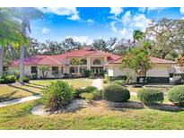 Expansive single-story home featuring a red tile roof, lush landscaping and a well-manicured front yard at 1616 Huntington Pl, Safety Harbor, FL 34695