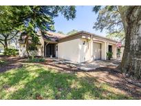 Charming single-story home with well-manicured lawn and attached garage, nestled under mature trees at 2201 Pine Dr, Tarpon Springs, FL 34689