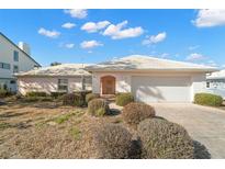 Charming single-story home featuring a white tile roof, front-facing garage, and lovely, low-maintenance landscaping at 10427 Spoonbill W Rd, Bradenton, FL 34209