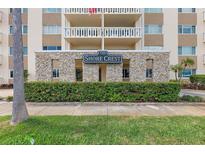 Exterior daytime view of the Shore Crest condominium building entrance with stone trim, and green foliage at 1200 N Shore Ne Dr # 102, St Petersburg, FL 33701
