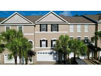 Charming townhome featuring a two-car garage, neutral paint, and mature palm trees at 14 Seagrape Cir, Clearwater, FL 33759