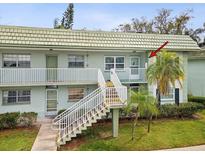 Two-story condo building with white railings, staircase and tropical landscaping at 1433 S Belcher Rd # F20, Clearwater, FL 33764