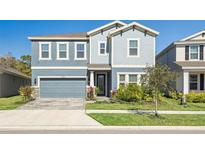 Charming two-story home showcasing a welcoming blue exterior, manicured lawn, and an attached two-car garage at 17953 Ramble On Way, Land O Lakes, FL 34638