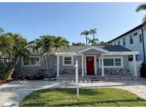 Charming one-story home featuring stone accents, a bright red door, and lush landscaping at 3419 W Empedrado St, Tampa, FL 33629