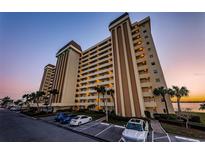 Multi-story tan condo building featuring numerous balconies and meticulous landscaping at 4525 Cove Cir # 705, St Petersburg, FL 33708