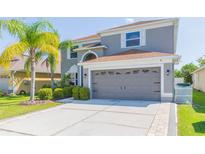 Charming two-story home with a well-manicured lawn, a gray exterior and a two-car garage, complemented by a concrete driveway at 7352 Cutwater Ln, Wesley Chapel, FL 33545