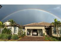 Charming home with a tile roof, lush landscaping, and a vibrant rainbow in the background at 13100 Rinella St, Venice, FL 34293