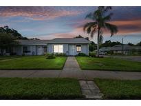 Charming single-story villa with a well-manicured lawn and sidewalk leading to the front door at 211 Somerset Cirle N, Dunedin, FL 34698