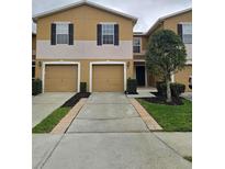 Inviting townhouse featuring a well-maintained lawn, two-car garage, and neutral exterior color scheme at 4224 Winding River Way, Land O Lakes, FL 34639