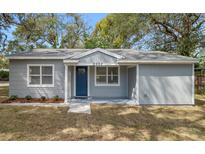 Charming single-story home with a fresh gray exterior, blue front door and well-maintained yard at 6802 N 15Th St, Tampa, FL 33610
