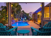 A stunning backyard pool with a waterfall and lush tropical landscaping viewed from the covered lanai at 725 Monte Cristo Blvd, Tierra Verde, FL 33715