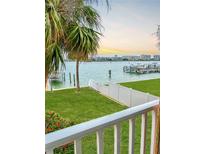 Beautiful waterfront view featuring palm trees, green grass, and condos in the distance at 8901 Blind Pass Rd # 224, St Pete Beach, FL 33706