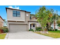 Charming two-story home featuring a neutral-toned facade, attached garage, and well-maintained landscaping at 11201 Hudson Hills Ln, Riverview, FL 33579
