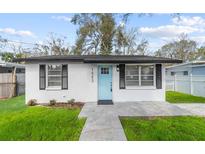 Charming home featuring a light blue front door, black shutters, and freshly cut lawn at 1503 W Hamilton Ave, Tampa, FL 33604