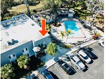 An aerial view of the condo complex featuring a pool, parking area, and lush landscaping at 700 Lyndhurst St # 1024, Dunedin, FL 34698