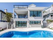Home's backyard features an inviting pool, a modern design, and a staircase leading to upper levels at 8505 Blind Pass Dr, Treasure Island, FL 33706
