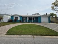 Charming blue home with a well-manicured lawn, brick driveway, and a one car garage at 12734 2Nd Isle, Hudson, FL 34667