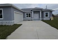 Charming home featuring a two-car garage, gray stucco exterior, and a concrete driveway at 14300 Kay Ln, Port Charlotte, FL 33981