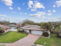 Aerial view of the front exterior showcasing a well-manicured lawn, brick driveway, and a home with solar panels at 1508 Cascade Ct, Dunedin, FL 34698