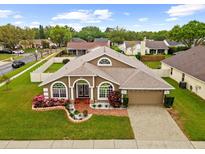 Inviting single-Gathering home featuring a well-manicured lawn and attached two-car garage at 2015 Golf Manor Blvd, Valrico, FL 33596