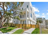 Modern townhouse with a white facade, balcony, and a wooden fence surrounding the landscaped front yard at 307 15Th N St, St Petersburg, FL 33705