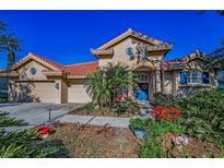 Charming single-Gathering home showcasing a well-manicured lawn and colorful landscaping with a welcoming blue front door at 4677 Aylesford Dr, Palm Harbor, FL 34685