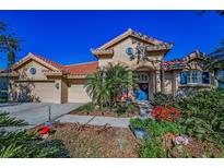 Charming single-Gathering home featuring a red tile roof, blue front door, and well-maintained landscaping at 4677 Aylesford Dr, Palm Harbor, FL 34685