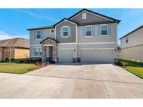 Two story home with a two car garage, light gray paint, stone entryway and shutters on the windows at 8816 Mugnai St, Riverview, FL 33578