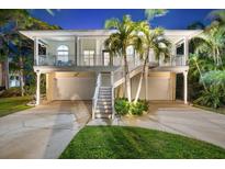 Two-story home with a double garage, white stairs, and a charming front balcony with palm trees at 1051 Point Seaside, Crystal Beach, FL 34681
