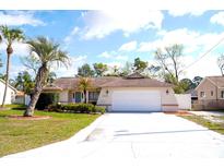 Charming single-story home with well-maintained landscaping, a driveway, and a two-car garage at 13112 Groveland St, Spring Hill, FL 34609