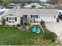 Charming single-story home with a well-manicured lawn, blue Adirondack chairs, and a decorative nautical theme at 1350 Maple Sw St, Largo, FL 33770