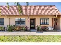 Charming home featuring a lovely garden bed, well-kept lawn, and unique terracotta-colored tile roof at 19029 Us Highway 19 N # 30H, Clearwater, FL 33764