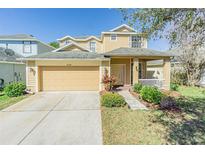 Charming two-story home with a well-manicured lawn, inviting front porch, and attached two car garage at 20326 Merry Oak Ave, Tampa, FL 33647