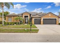 Inviting single-Gathering home featuring manicured lawn, mature trees, and a three-car garage at 20849 Cedar Bluff Pl, Land O Lakes, FL 34638