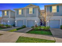 Two-story townhome featuring blue siding, well-manicured landscaping, and attached garages at 2109 Laceflower Dr, Brandon, FL 33510