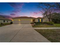 Inviting home with a three-car garage and a well-manicured lawn at dusk at 5325 Sandy Shell Dr, Apollo Beach, FL 33572