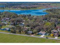 An aerial view highlights the property's location near a beautiful lake, complemented by lush greenery and clear skies at 10925 Fort King Rd, Dade City, FL 33525