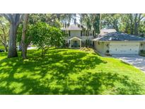 Beautiful two-story home featuring a lush front yard with mature trees and attached two-car garage at 1857 Castle Woods Dr, Clearwater, FL 33759