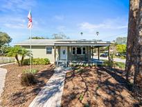 Charming single story home with a covered porch, walkway, and an American flag at 470 Hibiscus N Ln, Dunedin, FL 34698