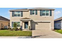 Two-story home with a two-car garage, blue shutters and a well-manicured lawn at 5456 Logan Cave Ave, Wimauma, FL 33598