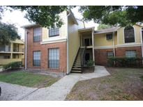 Two-story condo featuring brick and siding exterior with covered entry and a stairway to the second floor at 8728 Mallard Reserve Dr # 102, Tampa, FL 33614
