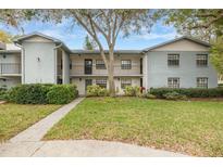 Two-story condo building with green lawn, sidewalk, and lush landscaping at 11800 Park Blvd # 505, Seminole, FL 33772