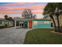 Charming exterior view of a one-story home showcasing colorful accents, a paved driveway, and mature landscaping at 1868 Douglas Ave, Dunedin, FL 34698