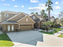 Stately two-story home featuring a large driveway, three-car garage, tan facade and well manicured landscaping at 19238 Climbing Aster Dr, Tampa, FL 33647