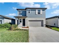 Charming two-story home with a gray two car garage, well-maintained lawn, and neat landscaping at 3204 Fresno Pl, Zephyrhills, FL 33541