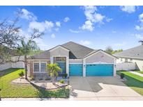 Charming single-Gathering home featuring a three-car garage and eye-catching turquoise doors at 13235 Graham Yarden Dr, Riverview, FL 33579