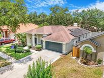 Inviting one-story home with a two-car garage, lush landscaping, and solar panels on the roof at 3616 Cypress Meadows Rd, Tampa, FL 33624