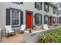 Charming townhome with a bright red door, black shutters, and a cozy front porch sitting area at 6134 Fishhawk Crossing Blvd, Lithia, FL 33547